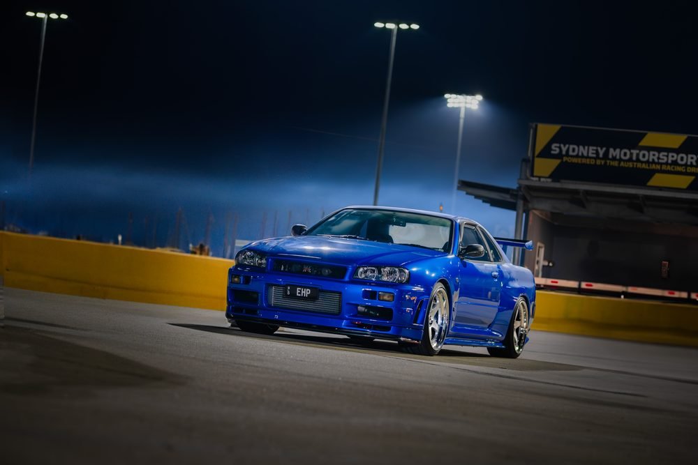 Blue Nissan Skyline R34 GT-R on track at Sydney Motorsport Park under night lighting
