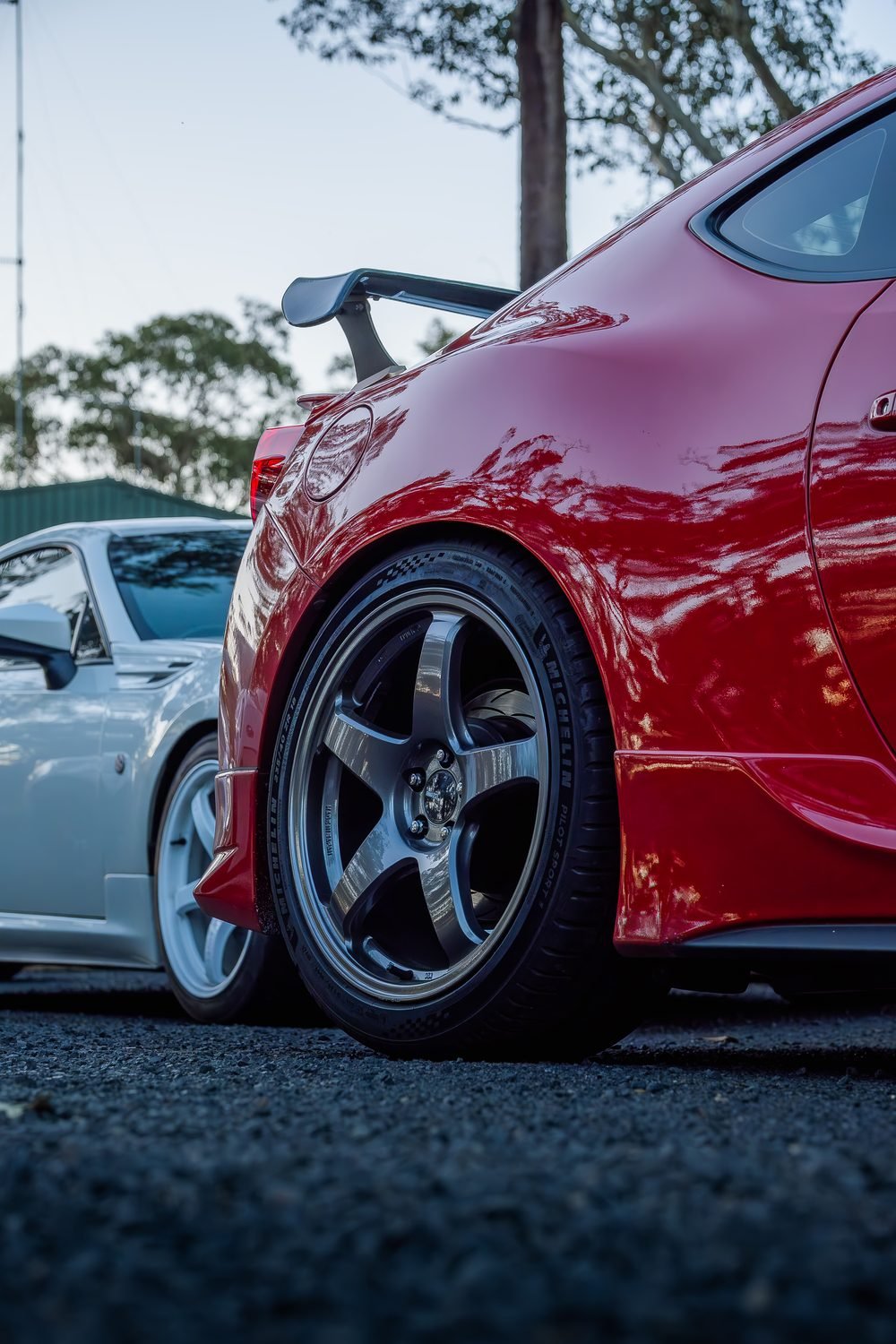 Red sports coupe rear quarter on forged wheels at a country car meet