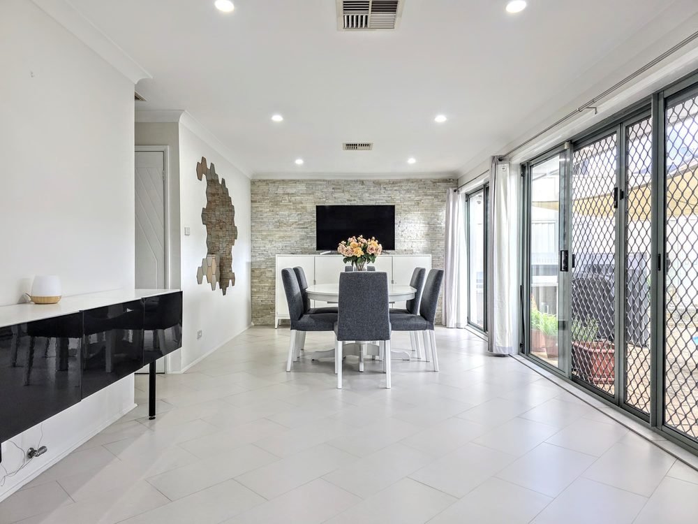 Open-plan dining room with a stone feature wall and sliding doors to the patio
