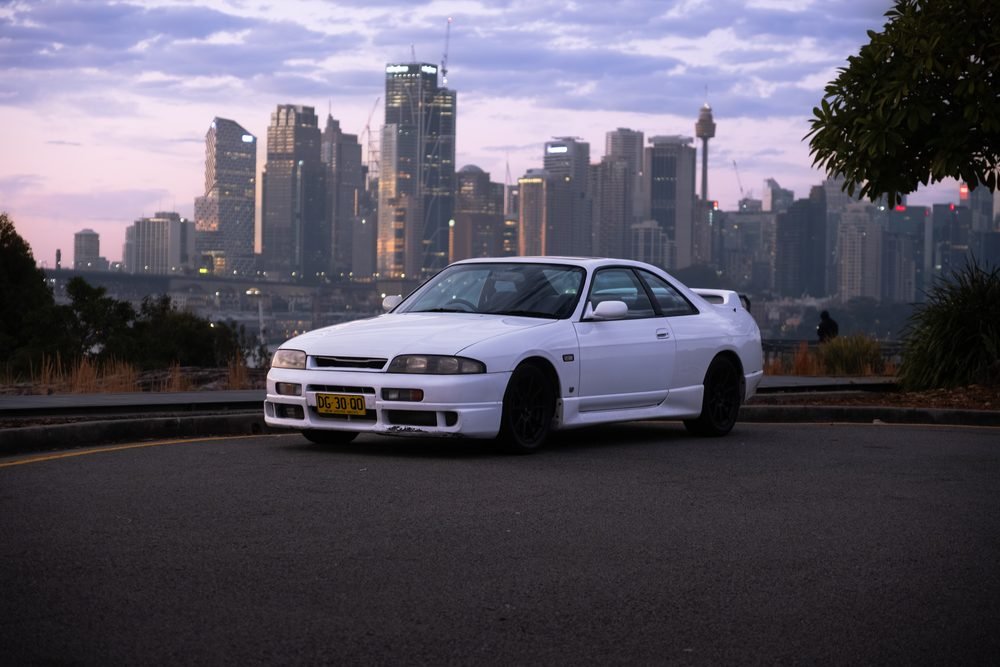 White Nissan Skyline GTS at a lookout above Sydney Harbour at sunset
