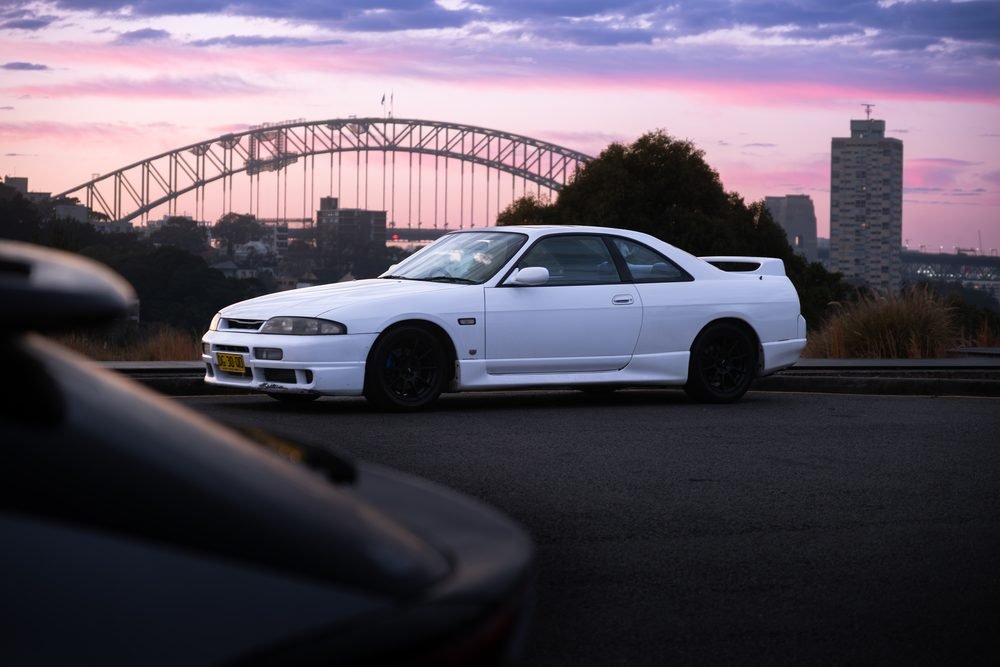 Nissan Skyline GTS photographed against the Sydney city skyline and Harbour Bridge at sunset (frame 5 of 12)