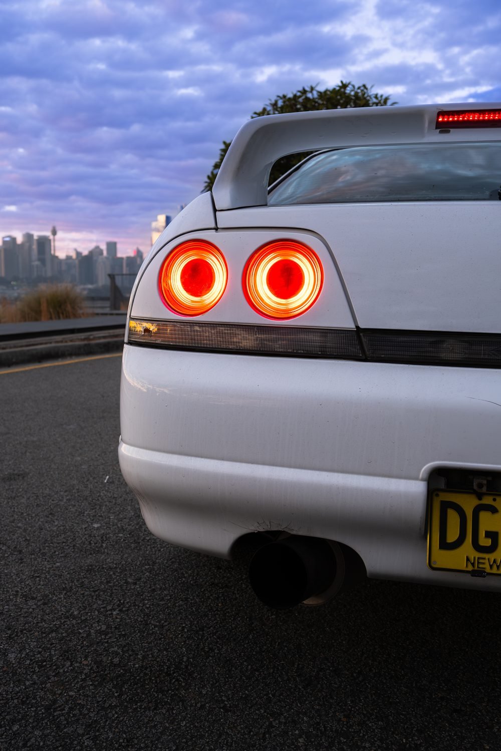 Nissan Skyline GTS photographed against the Sydney city skyline and Harbour Bridge at sunset (frame 7 of 12)