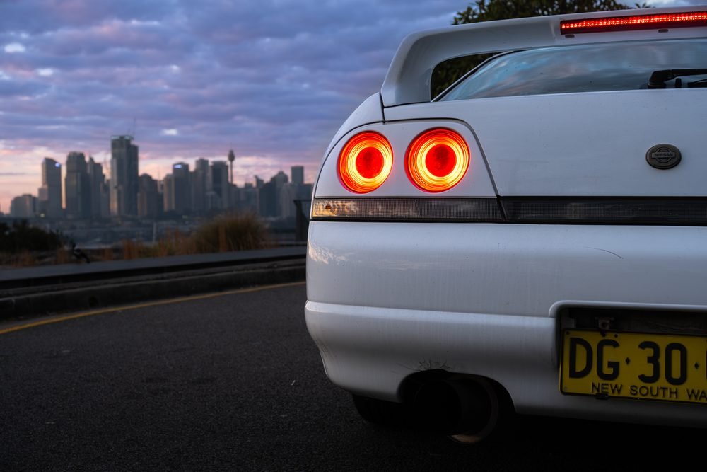 Nissan Skyline GTS photographed against the Sydney city skyline and Harbour Bridge at sunset (frame 8 of 12)