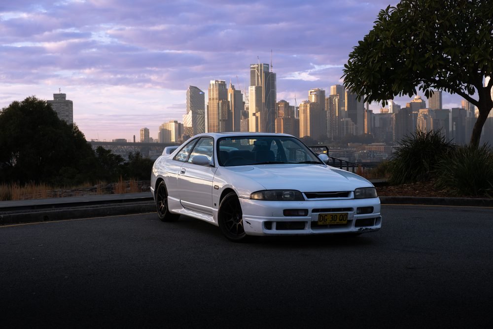 Nissan Skyline GTS photographed against the Sydney city skyline and Harbour Bridge at sunset (frame 10 of 12)